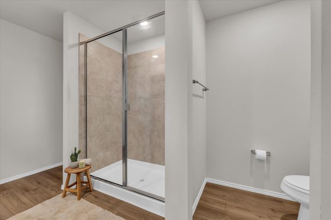 Bathroom with a stall shower, wood finished floors, toilet, and baseboards | Image 12