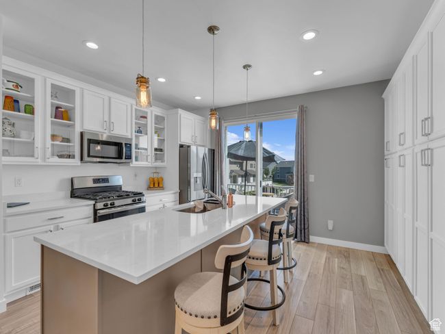 Kitchen with stainless steel appliances, an island with sink, a kitchen bar, recessed lighting, and white cabinetry | Image 9