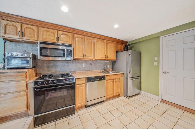 Kitchen with stainless steel appliances, light countertops, a sink, backsplash, and recessed lighting | Image 21