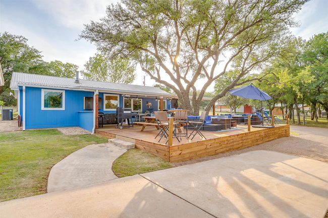 Back of property with outdoor lounge area, a wooden deck, outdoor dining area, a lawn, and metal roof | Image 11