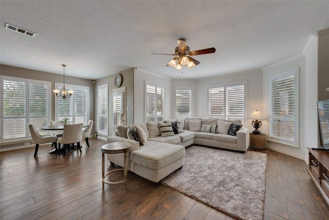 Living room featuring wood-type flooring, crown molding, and ceiling fan with notable chandelier | Image 8