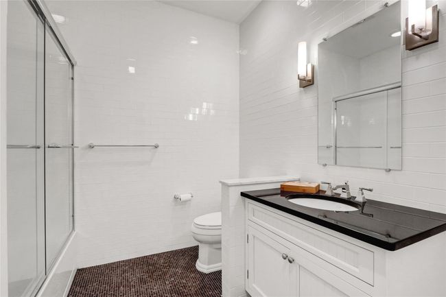 Bathroom featuring tile walls, toilet, vanity, tile patterned flooring, and shower / bath combination with glass door | Image 20