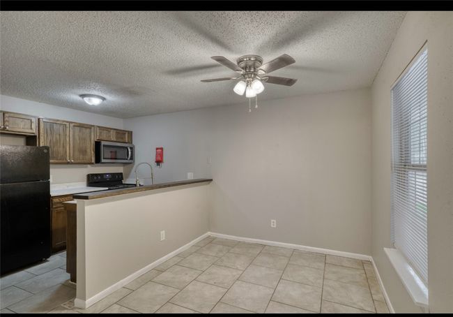 Kitchen featuring freestanding refrigerator, stainless steel microwave, range with electric stovetop, a peninsula, and ceiling fan | Image 15