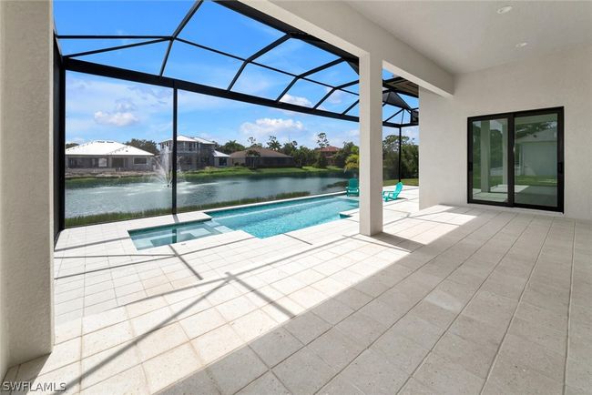 Large Lanai and Pool deck with upgraded white coral pavers, spa, pool sun shelf and lake/water fountain view. | Image 17