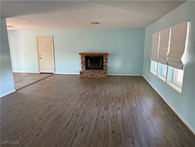 living room featuring dark wood-style floors, baseboards, and a brick fireplace | Image 10