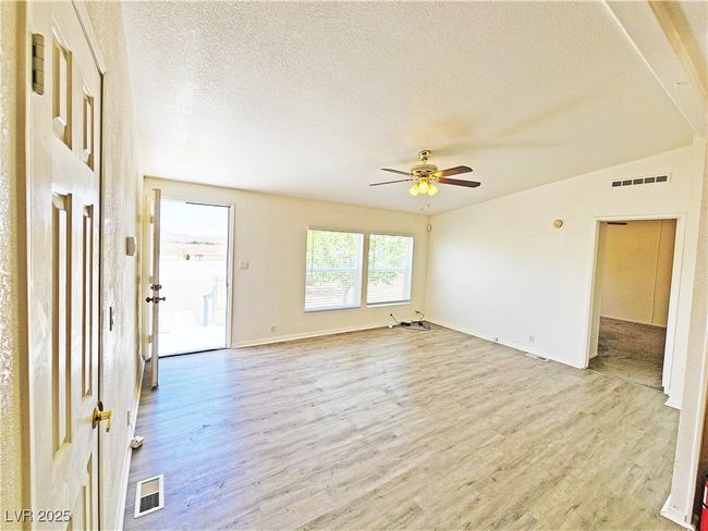Empty room with a textured ceiling, visible vents, and light wood finished floors | Image 4