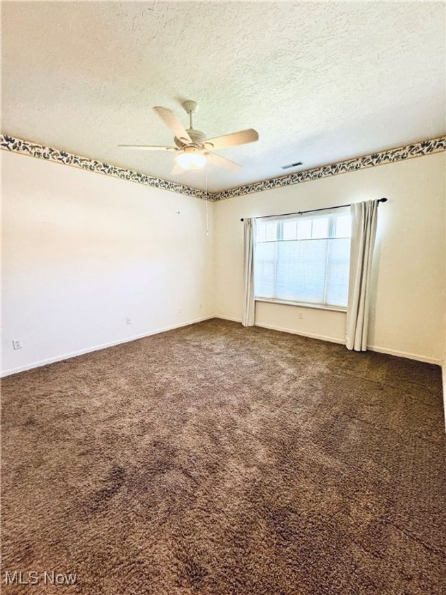 Spare room featuring dark carpet, a ceiling fan, and a textured ceiling | Image 19