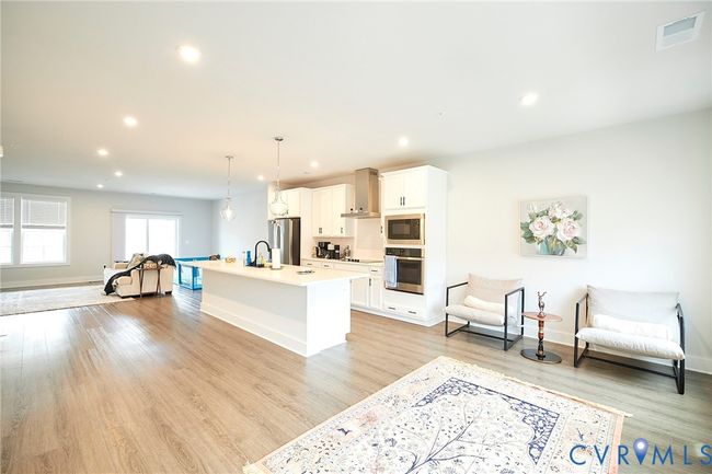 Kitchen with white cabinetry, appliances with stainless steel finishes, an island with sink, recessed lighting, and light wood-style floors | Image 40