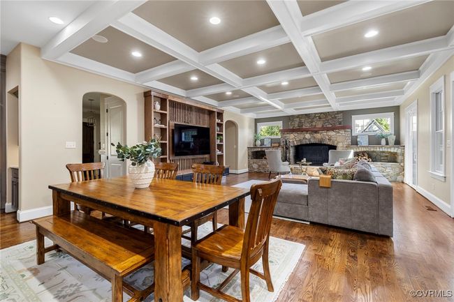 Dining space featuring arched walkways, a stone fireplace, wood finished floors, coffered ceiling, and beamed ceiling | Image 14