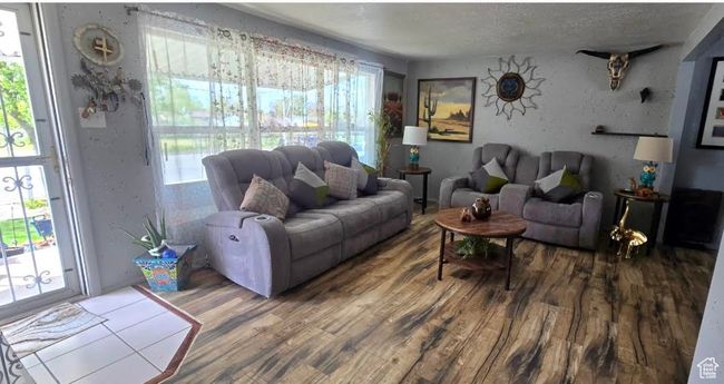 Living area with plenty of natural light, wood finished floors, and a textured ceiling | Image 4