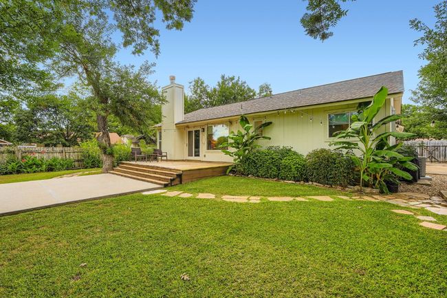 Back of property featuring a deck, a shingled roof, a chimney, and a patio area | Image 28
