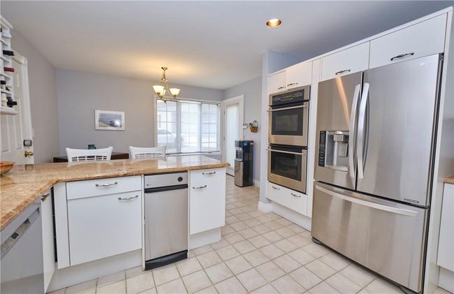 Kitchen with light tile patterned floors, appliances with stainless steel finishes, kitchen peninsula, and white cabinets | Image 21
