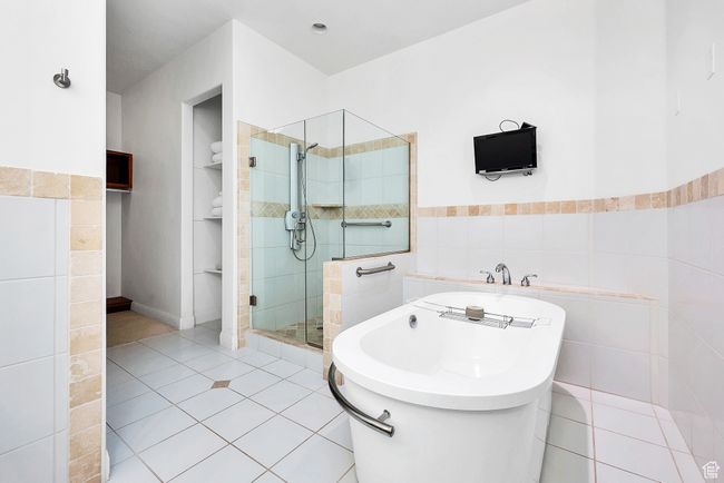 Bathroom featuring tile patterned floors, a freestanding bath, tile walls, wainscoting, and a shower stall | Image 22