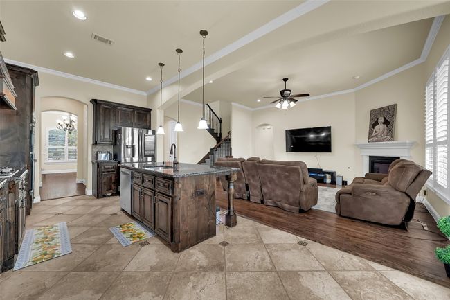 Kitchen featuring arched walkways, dark brown cabinets, open floor plan, decorative light fixtures, and a breakfast bar area | Image 12