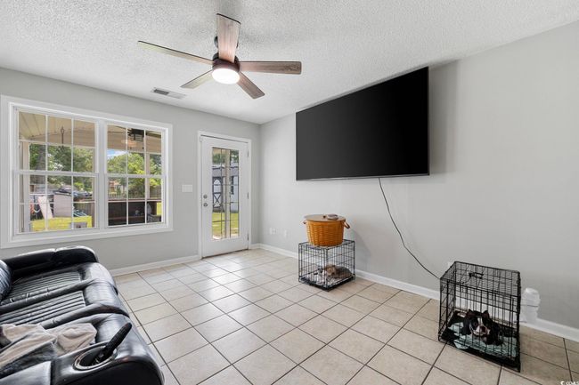 Living area with a textured ceiling, a ceiling fan, light tile patterned floors, and baseboards | Image 33