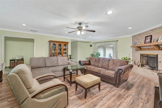 Living room featuring wood finished floors, ceiling fan, recessed lighting, ornamental molding, and a fireplace | Image 12