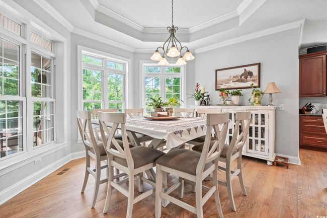 Dining room with a raised ceiling, a chandelier, light wood-type flooring, baseboards, and ornamental molding | Image 12