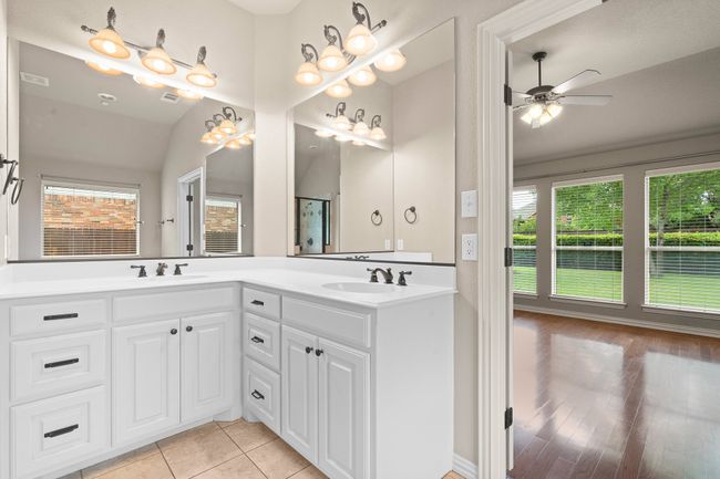 Full bathroom featuring healthy amount of natural light, double vanity, ceiling fan, vaulted ceiling, and an enclosed shower | Image 21