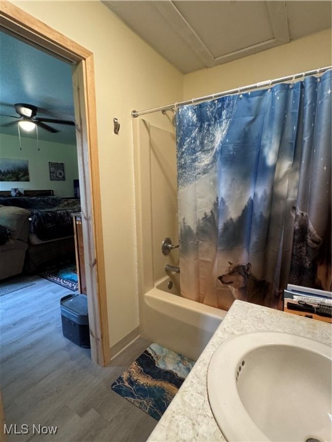 Bathroom featuring shower / tub combo with curtain, wood finished floors, vanity, and a ceiling fan | Image 20