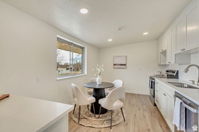 Kitchen with stainless steel appliances, light wood-style flooring, a sink, recessed lighting, and light countertops | Image 8