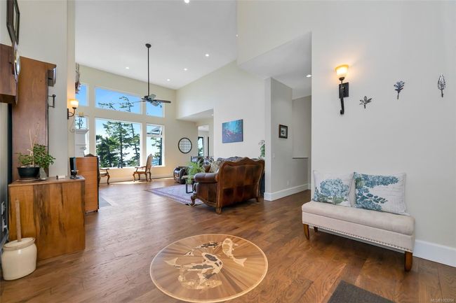 Sitting room with a water view, wood finished floors, and a towering ceiling | Image 6