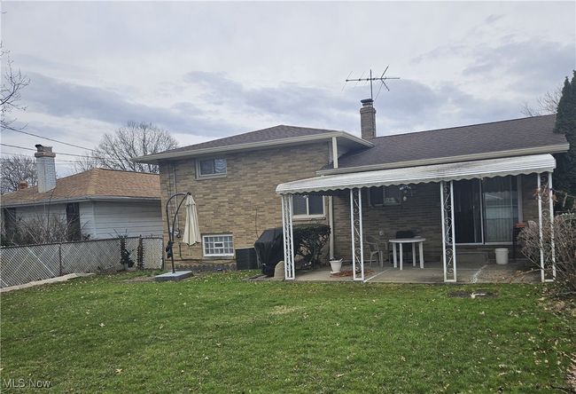 Back of house with a chimney, fence, a patio, a lawn, and brick siding | Image 12