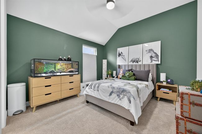 Secondary bedroom with vaulted ceiling, large window for natural light, and plush carpet underfoot. Clean lines and a modern paint palette create a comfortable and versatile space. | Image 15