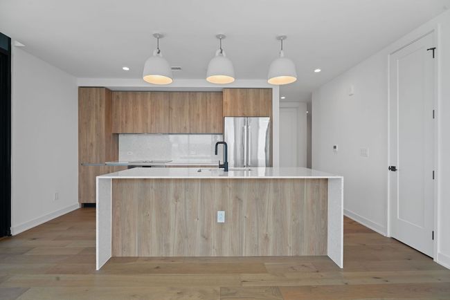 Kitchen with freestanding refrigerator, modern cabinets, light countertops, light wood-style flooring, and recessed lighting | Image 11