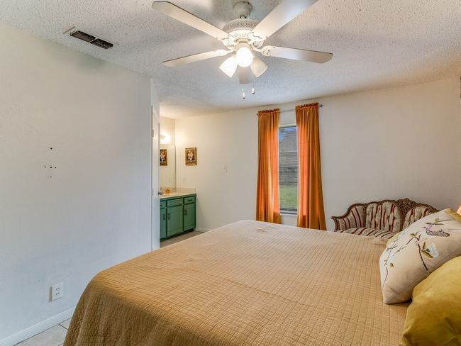 Bedroom featuring a textured ceiling, light colored carpet, ceiling fan, and ensuite bath | Image 24