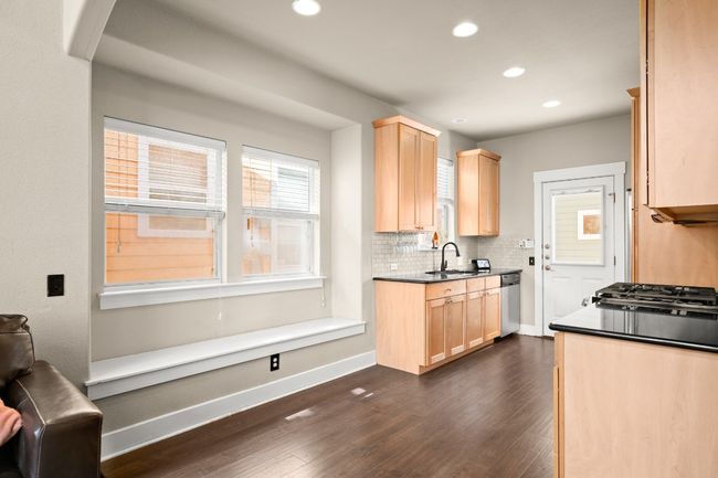 Kitchen featuring light brown cabinets, baseboards, dark wood finished floors, dark countertops, and backsplash | Image 9