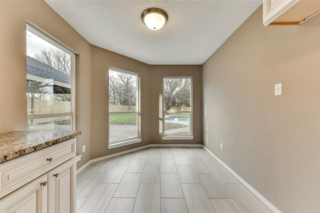 Unfurnished dining area with a textured ceiling and light tile patterned floors | Image 7
