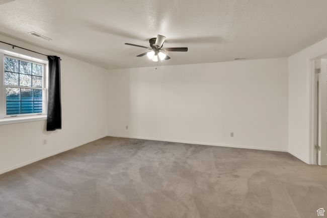 Empty room with a ceiling fan, a textured ceiling, baseboards, visible vents, and carpet | Image 18