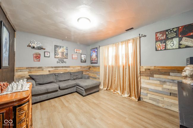 living room featuring wood finished floors, wooden walls, and visible vents | Image 20