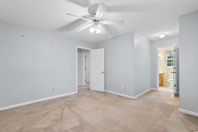 Unfurnished bedroom with light carpet, a textured ceiling, ceiling fan, and ensuite bathroom | Image 19