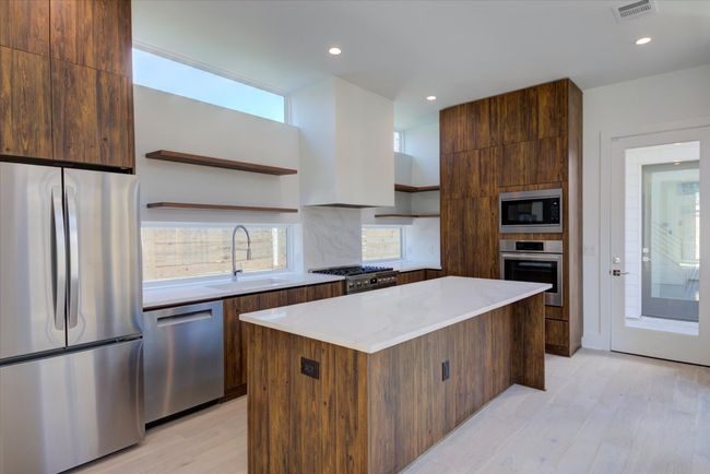 The chef's kitchen is adorned with custom walnut cabinetry, Bosch gas range/oven and Bosch built-in wall oven and Bosch drawer microwave. Easy access to the covered patio and climate controlled garage/flex room. | Image 9