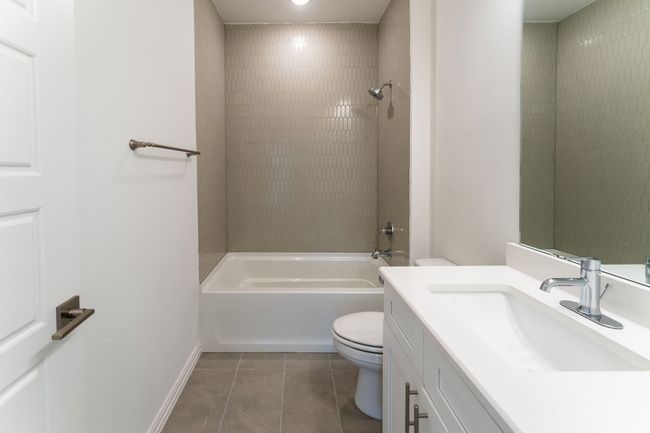 Bathroom with bathtub / shower combination, vanity, tile patterned flooring, toilet, and baseboards | Image 9