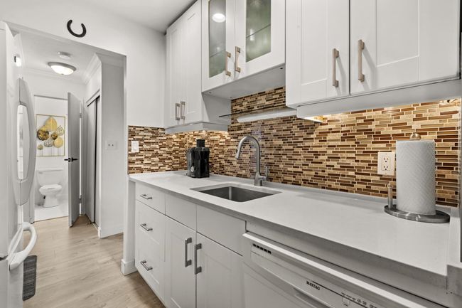 Kitchen featuring a sink, dishwasher, white cabinets, and freestanding refrigerator | Image 9