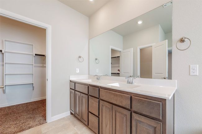 Full bath featuring double vanity, a walk in closet, and baseboards | Image 18
