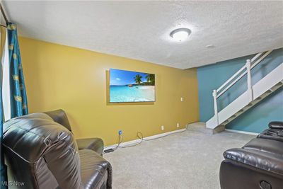 Carpeted living room featuring a textured ceiling | Image 2