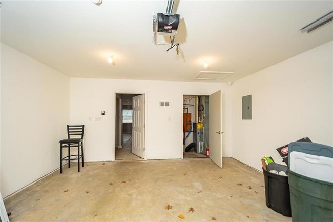 Garage with electric panel, visible vents, and a garage door opener | Image 36