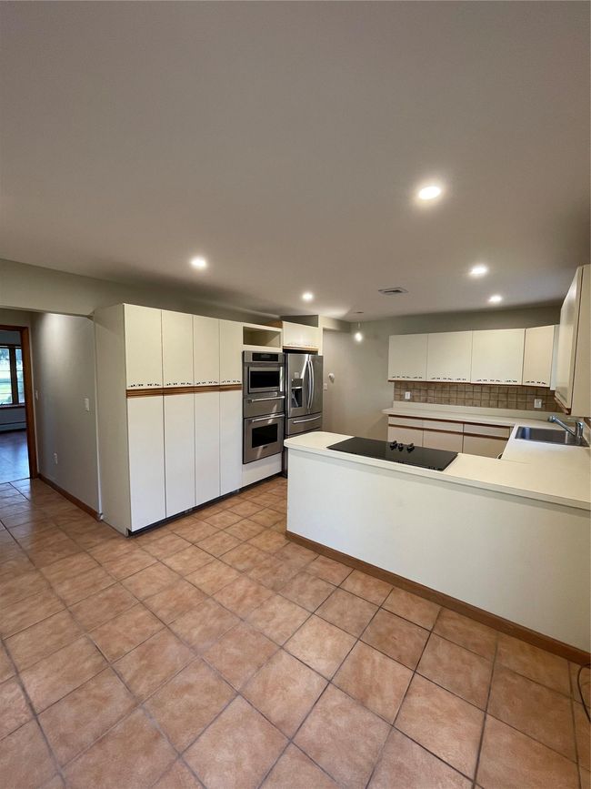 Kitchen with a sink, backsplash, stainless steel fridge, cooktop, and double oven | Image 7