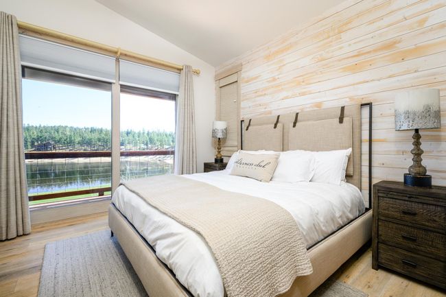 Elegant primary suite featuring a wall of glass doors opening to a large deck with views of the golf course and Wilderness Lake | Image 17