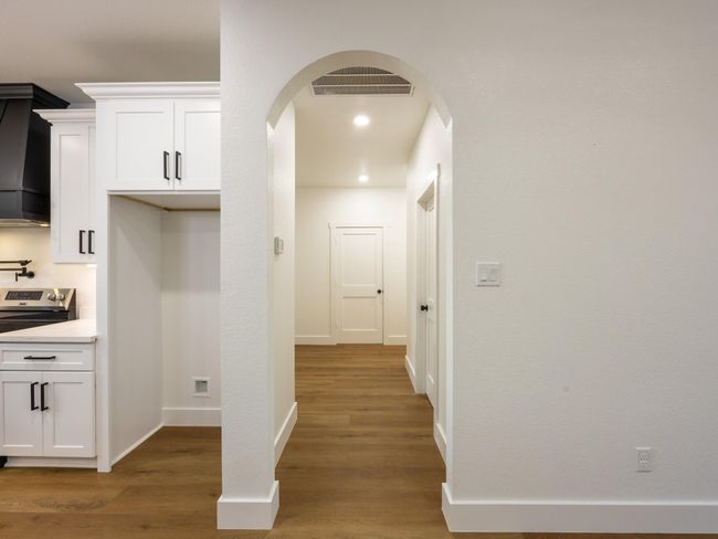 A graceful arched entry leads from the kitchen into the bedroom wing, adding architectural charm while maintaining the home’s clean, cohesive flow. | Image 18