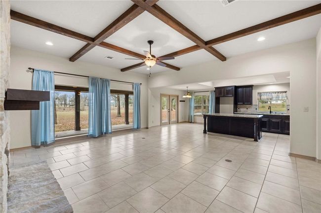 Unfurnished living room featuring light tile patterned flooring, coffered ceiling, a sink, baseboards, and beam ceiling | Image 6