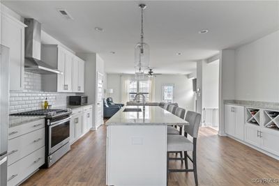 Kitchen featuring appliances with stainless steel finishes, light hardwood / wood-style flooring, wall chimney range hood, and sink | Image 2