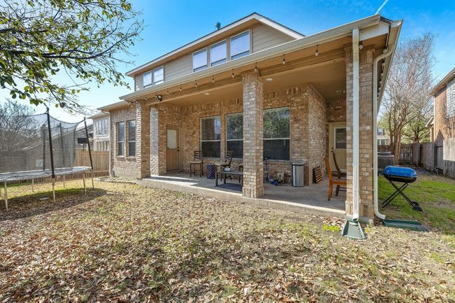 Back of property with brick siding, a trampoline, a patio area, and a fenced backyard | Image 26