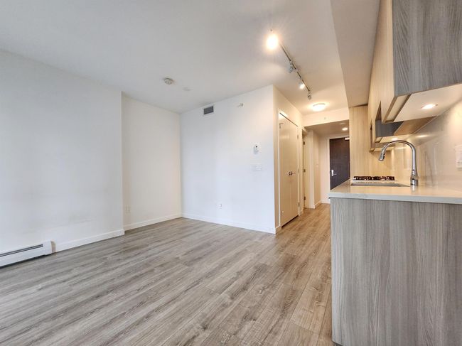 Unfurnished living room featuring rail lighting, light wood finished floors, baseboard heating, and baseboards | Image 7