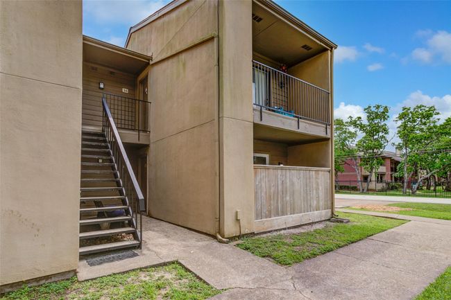 This photo shows a two-story apartment exterior with a staircase leading to the upper level. | Image 24