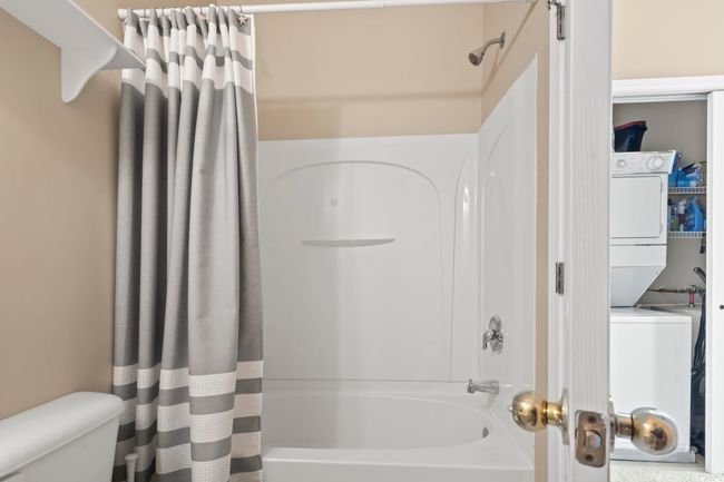 Bathroom with stacked washer / dryer, shower / bath combo, and toilet | Image 27