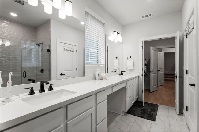 Bathroom with double vanity, a stall shower, marble finish floors, and recessed lighting | Image 13